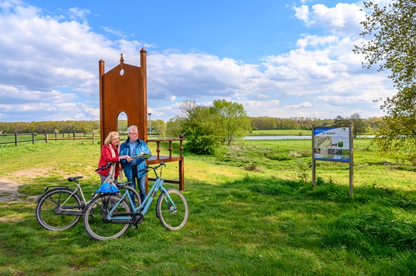 Vrouw en man kijken op de kaart bij het grote kunstwerk aan de Maas in Kessel