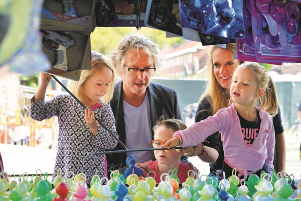 Dochters vissen naar eendjes op de Kermis in Weert terwijl mama, papa en broertje meekijken