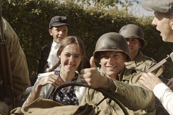 Geallieerde bevrijder rijdt met jong meisje in een jeep en steekt zijn duim op