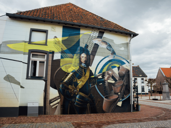 Muurschildering in Stevensweert van een man en een molen