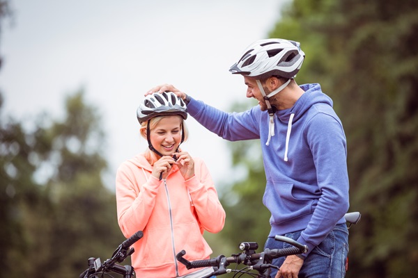 Stel maakt zich klaar voor een fietstocht door de fietshelm op te doen terwijl de man naar de vrouw lacht